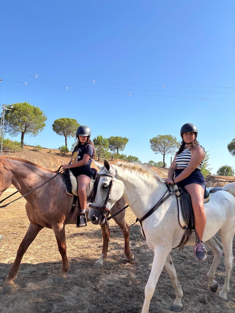 Dos participantes sobre dos caballos en la actividad de equitación.