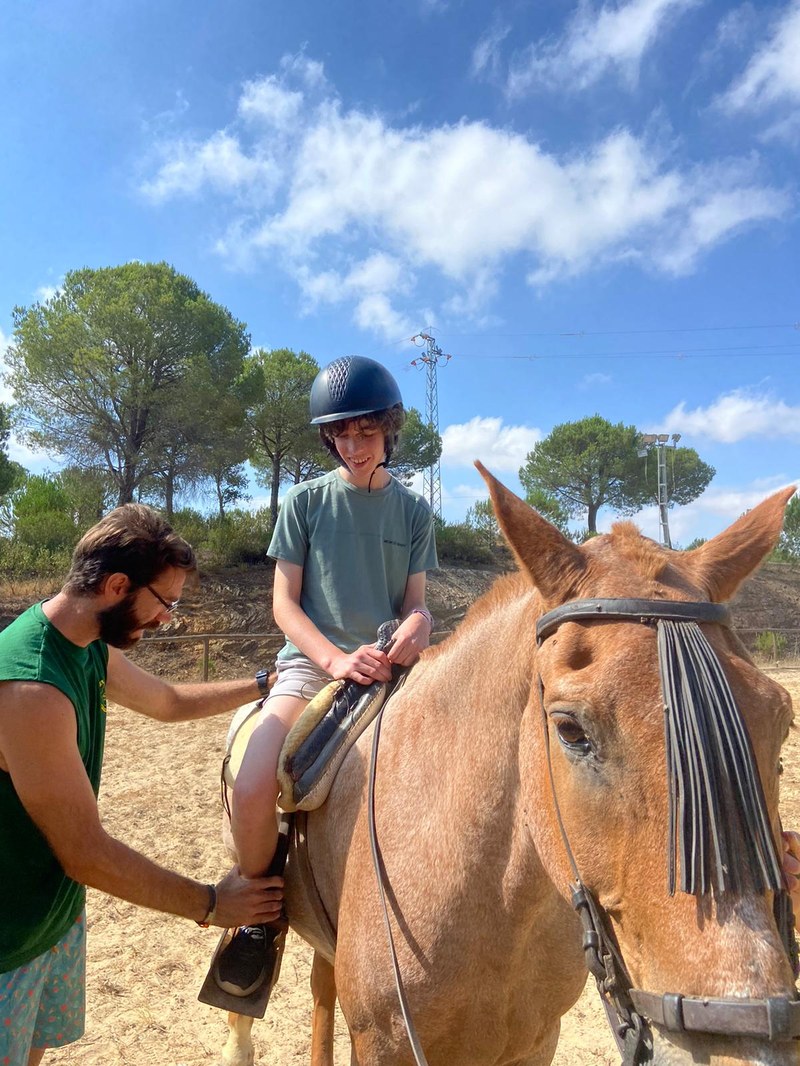 Un participante sobre un caballo recibe instrucciones de un monitor.