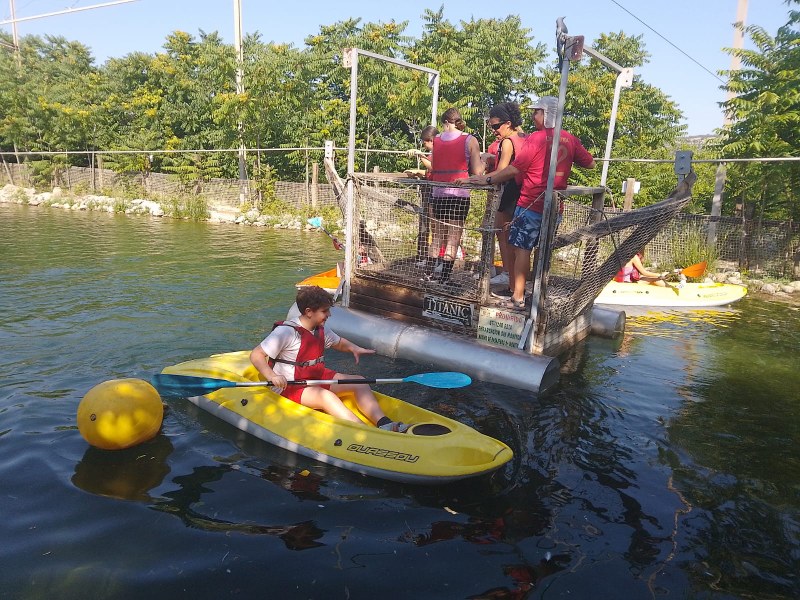 Actividad acuática en el embalse: un niño en una balsa y un grupo en el pantalán.