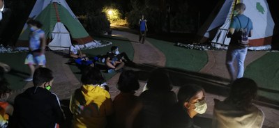 Varios niños sentados en la velada nocturna al lado de los tipis