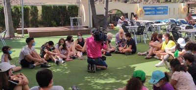 Dos chicos siendo entrevistados por la tele mientras el resto atiende Dos chicos siendo entrevistados por la tele mientras el resto atiende