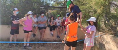 Niña haciendo slackline mientras algunos observan