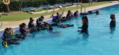 Grupo de niños atiende a las explicaciones de la monitora para hacer submarinismo en la piscina 2 Grupo de niños atiende a las explicaciones de la monitora para hacer submarinismo en la piscina 2