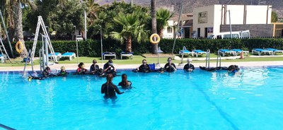 Grupo de niños atiende a las explicaciones de la monitora para hacer submarinismo en la piscina Grupo de niños atiende a las explicaciones de la monitora para hacer submarinismo en la piscina