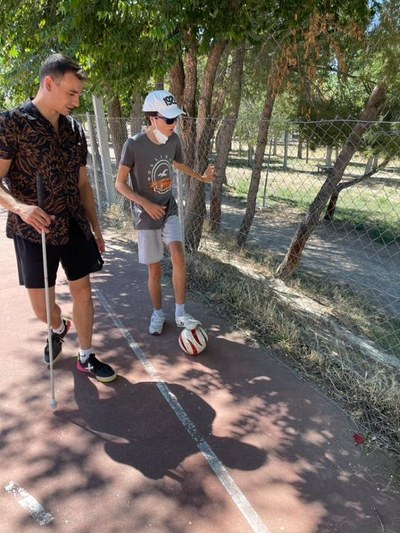 Monitor dando instrucciones a un niño con una pelota de fútbol Monitor dando instrucciones a un niño con una pelota de fútbol