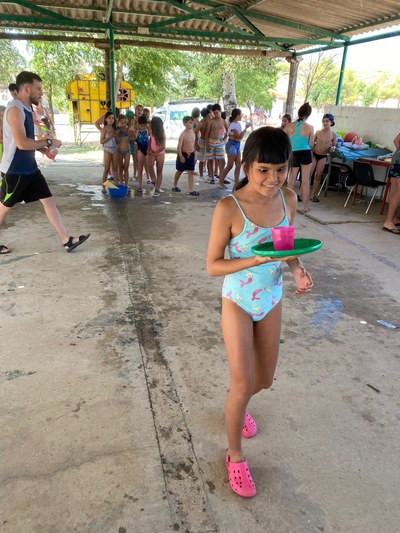 Niños más pequeños jugando a las gymkhanas con agua para que el calor sea un poco más llevadero