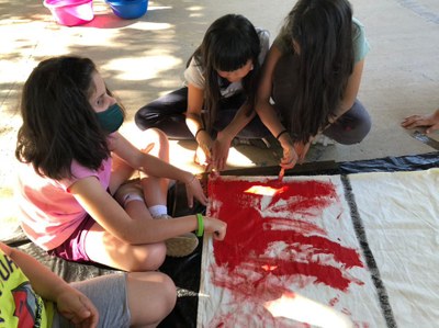 Tres niñas pintando banderas en el taller de pintura de telas