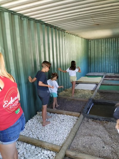 Tres niños con antifaz pisan descalzos diferentes superficies