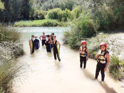 Chicos y chicas entrando en el agua para hacer rafting Chicos y chicas entrando en el agua para hacer rafting