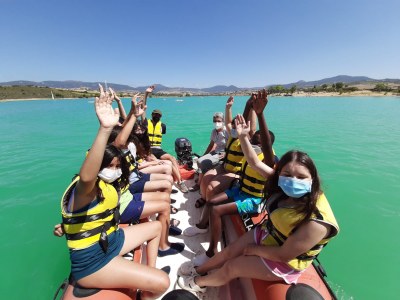Grupo de participantes saludando desde una lancha neumática Grupo de participantes saludando desde una lancha neumática