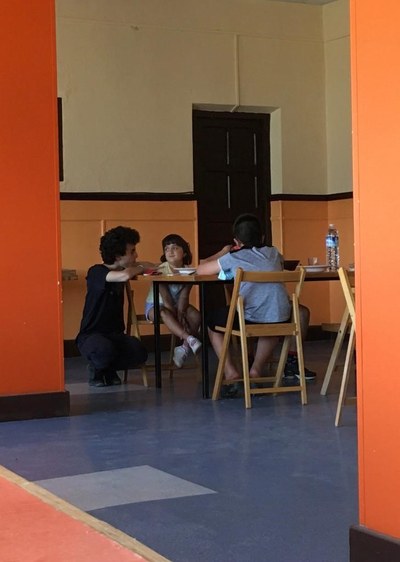 Un niño y una niña comen mientras hablan con un monitor Un niño y una niña comen mientras hablan con un monitor