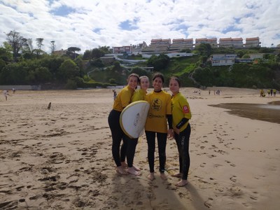 Cuatro participantes posan con una tabla de surf
