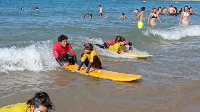 Dos participantes y dos monitores surfean una ola