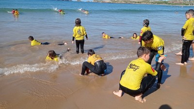 El grupo de pequeños hace una actividad de surf en el agua