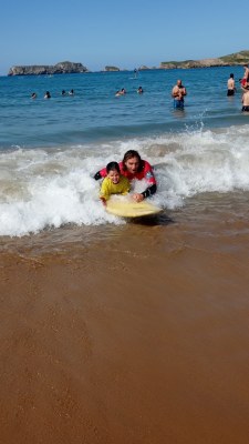 Una participante y un monitor surfean una ola