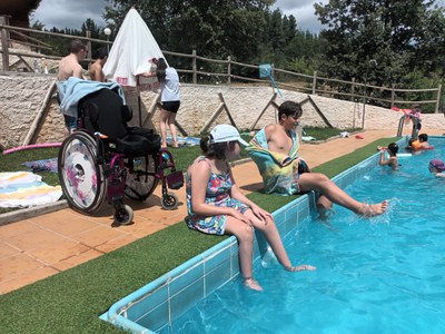 Dos participantes, sentados en el borde de la piscina, sumergen los pies en el agua