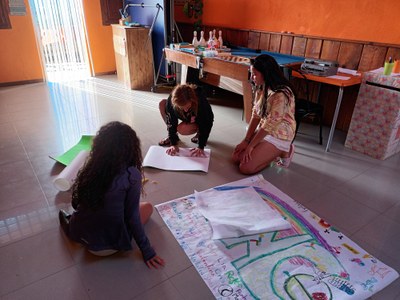 Dos participantes y una monitora, haciendo un cartel decorativo para la gala