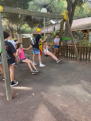 Grupo de participantes en un parque recreativo, dos de ellos subidos en un columpio
