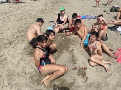 Un grupo de participantes alrededor de otro que tiene el cuerpo enterrado en la arena