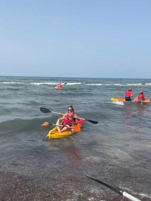 Un participante y monitora llegando a la orilla del mar en kayak