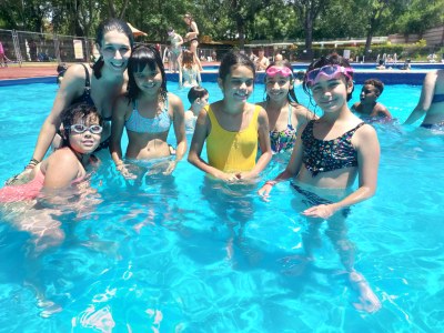 Un grupo de participantes, junto a una monitora, bañándose en la piscina