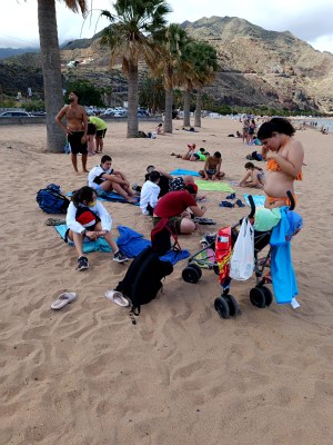 Varios participantes, al atardecer, sentados sobre la arena de la playa