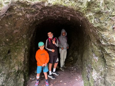 Tres participantes delante de una cueva