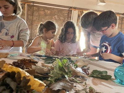 Unos participantes haciendo un paisaje con arcilla y elementos naturales Unos participantes haciendo un paisaje con arcilla y elementos naturales