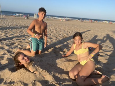 Tres participantes en la playa, juegan con la arena