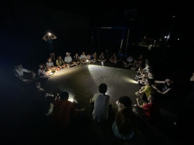 Los participantes, sentados en círculo, se alumbran con las linternas.