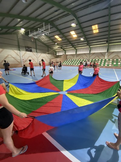 Un grupo de participantes hace un juego con una lona en el pabellón deportivo. 