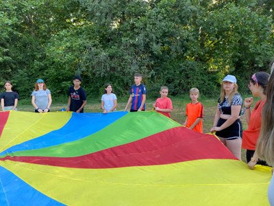 Varios participantes en círculo y con un paracaídas de colores