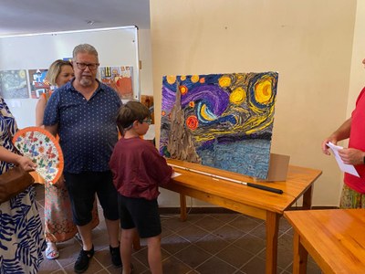 Un participante enseña la obra artística realizada para la exposición