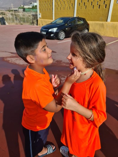 Dos participantes se pintan la cara el uno al otro