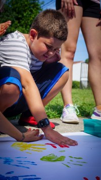 Participante plasmando su mano con pintura sobre el mural de las ONCEolimpiadas.