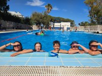 5 participantes apoyados en el borde de la piscina.