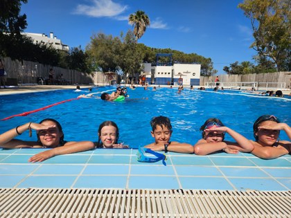 5 participantes apoyados en el borde de la piscina.