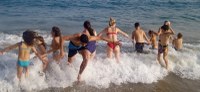 Grupo de participantes disfrutando del baño en la playa.