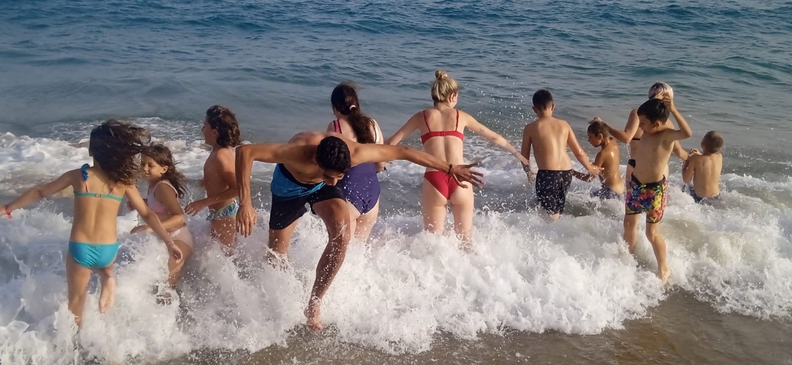 Grupo de participantes disfrutando del baño en la playa.