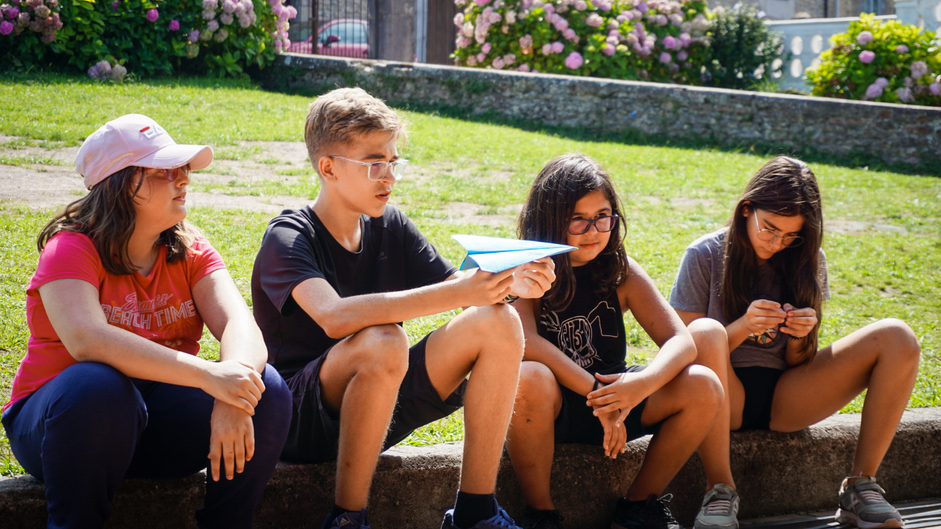 4 Participantes sentados sobre un bordillo escuchando las explicaciones.