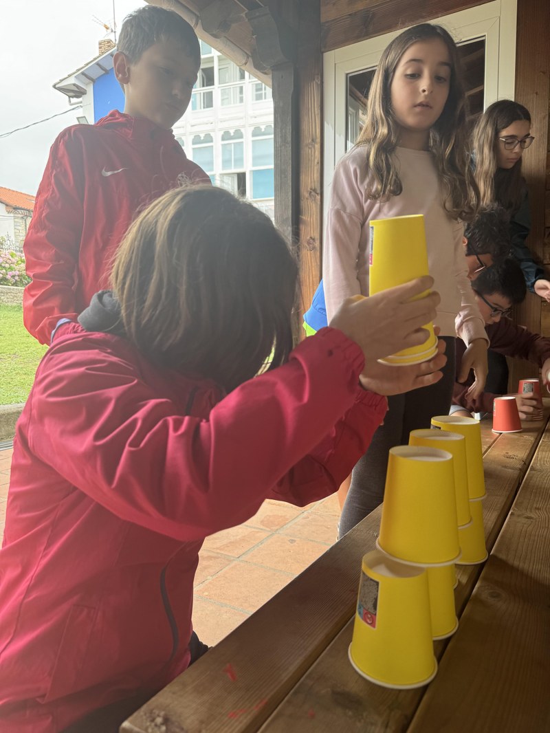 Participantes montando una torre de vasos durante los juegos de coordinación y velocidad.