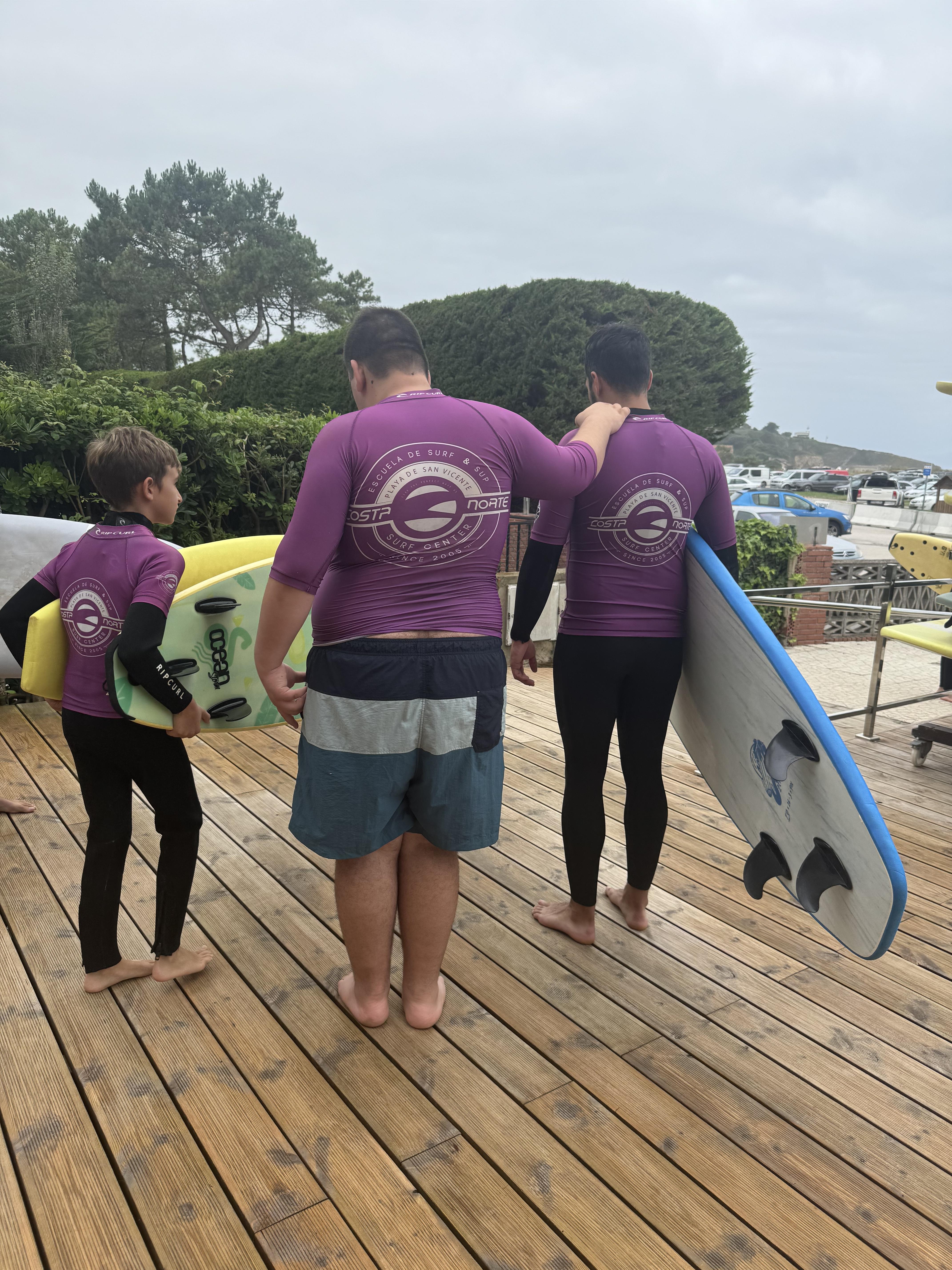 Participantes llevando las tablas de surf hacia la orilla, ayudándose unos a otros.