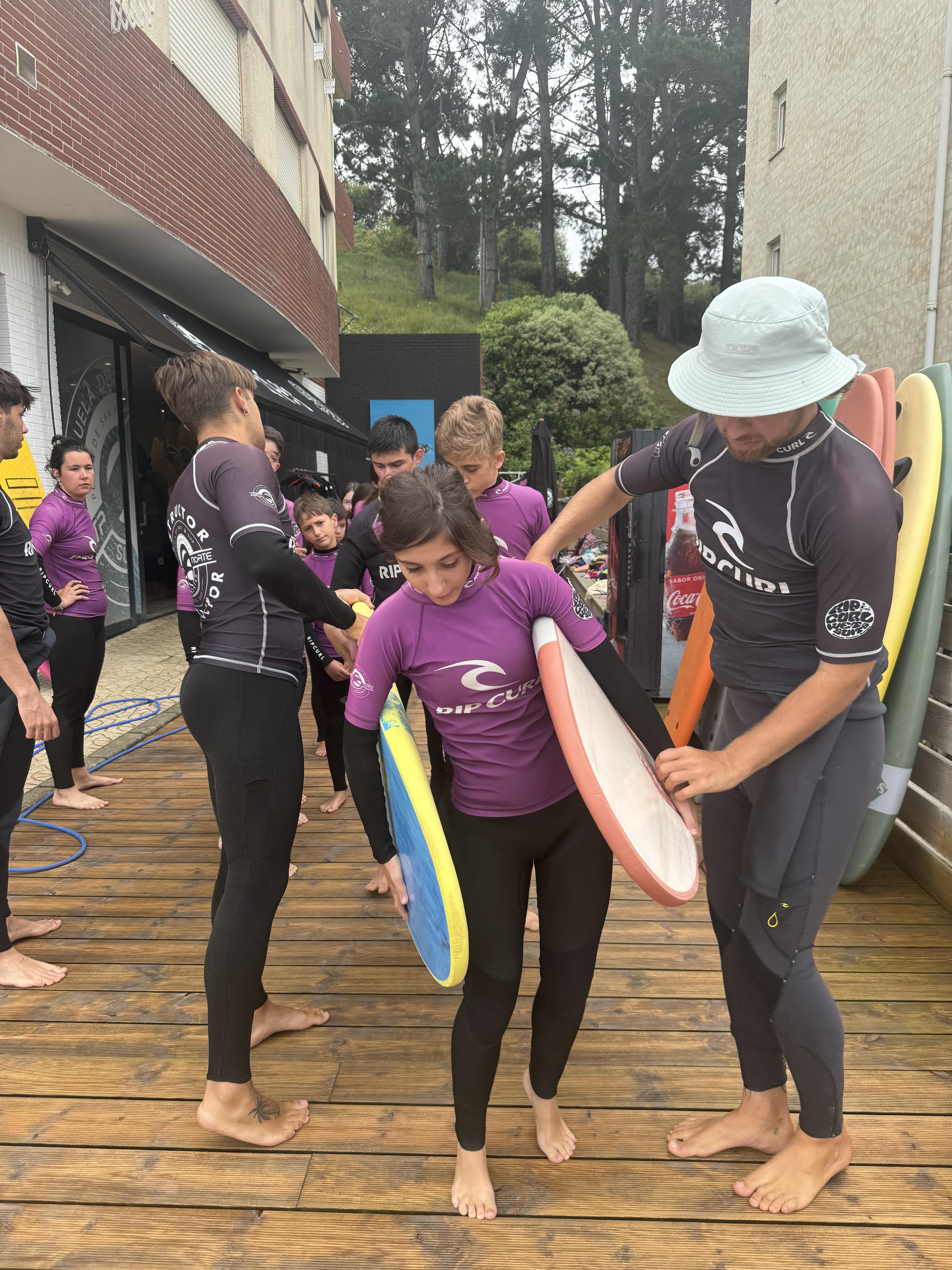 Participantes llevando las tablas de surf hacia la orilla, ayudándose unos a otros.