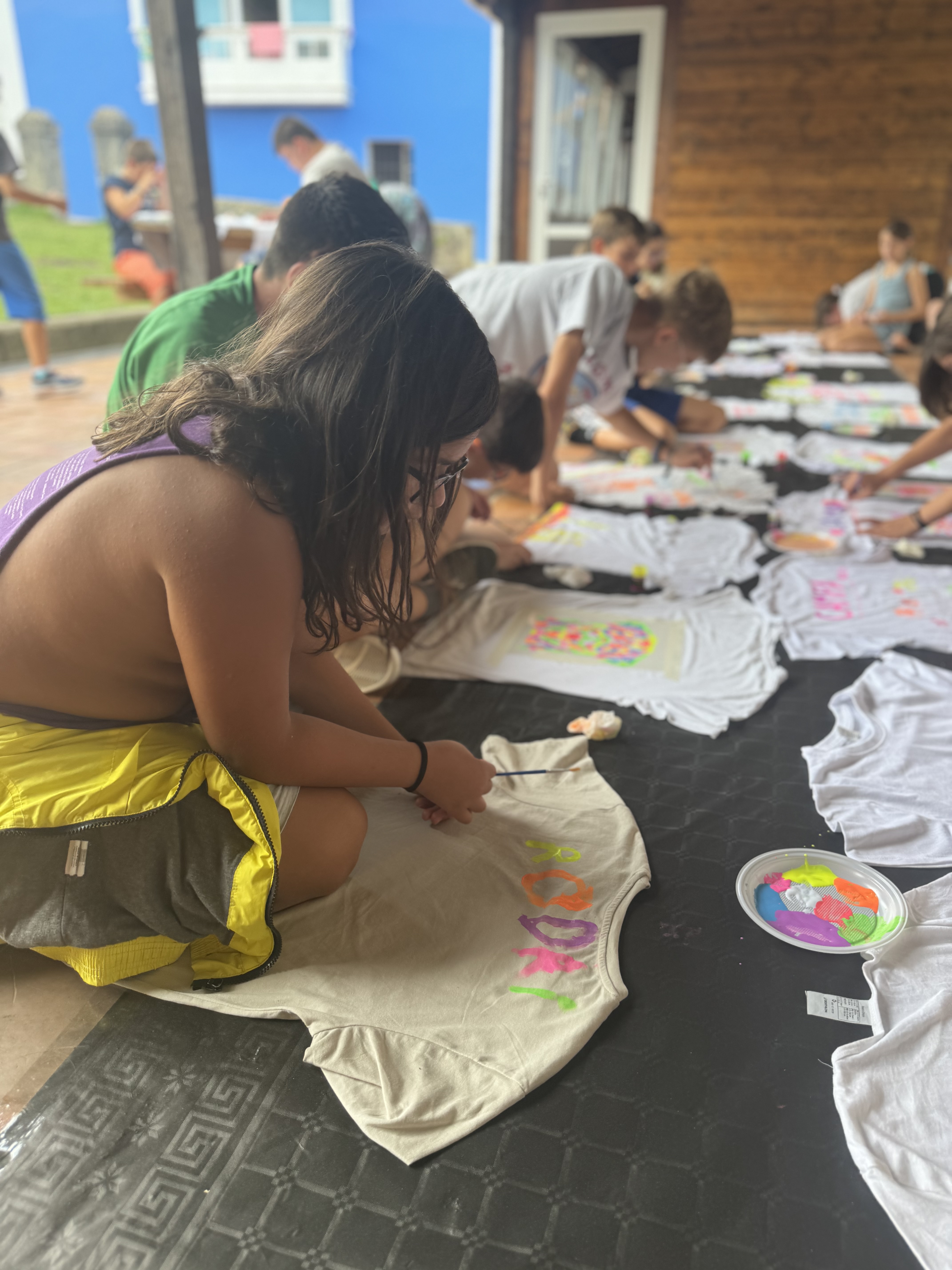 Participantes pintando sus camisetas con pinturas de neón.