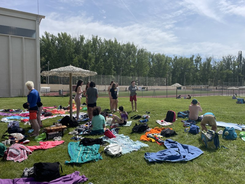 Grupo de participantes descansando en la zona de toallas durante el tiempo en la piscina.