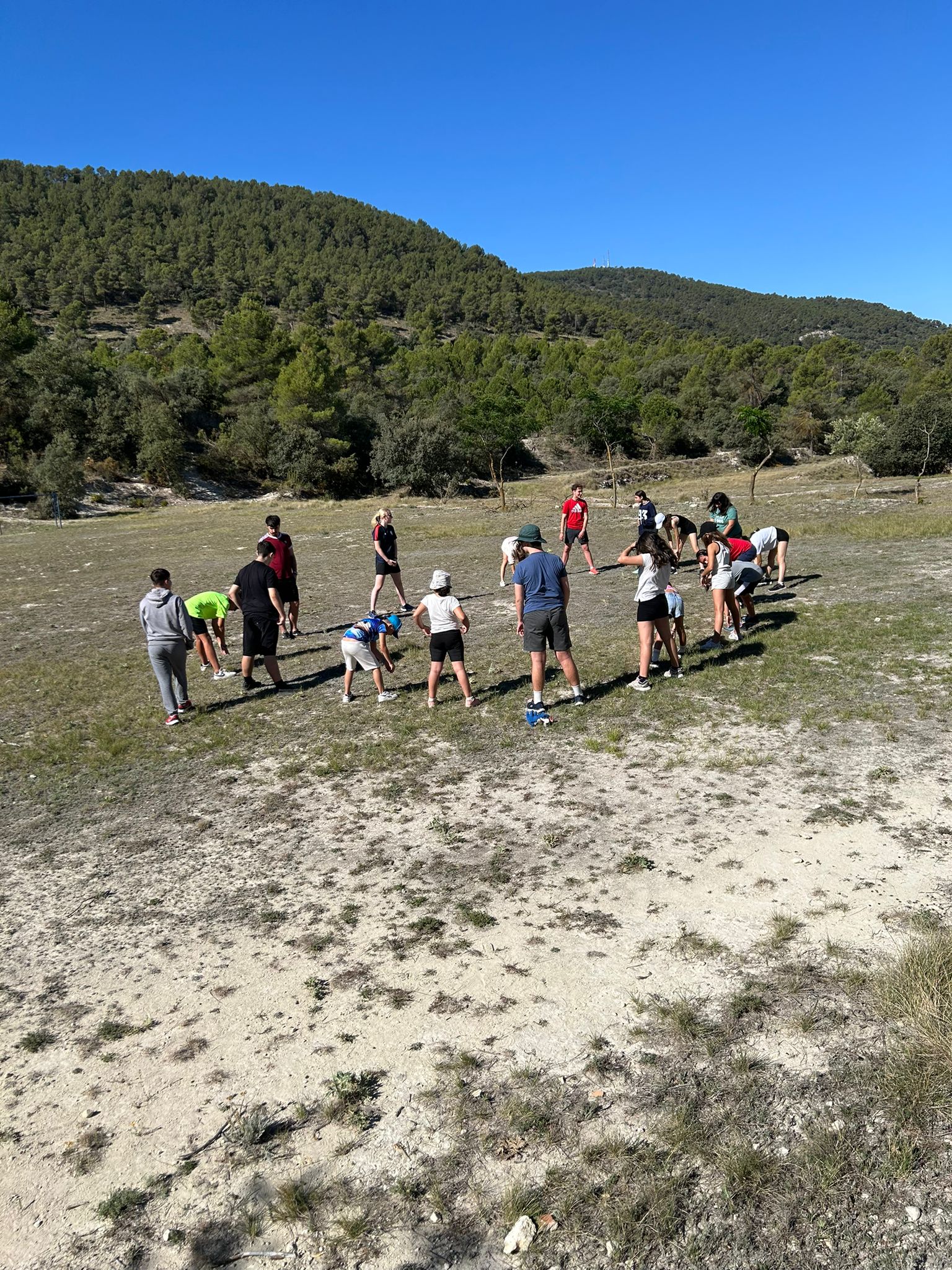 Grupo de participantes dispuestos en círculo haciendo ejercicios de calentamiento. 