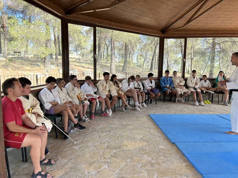 Participantes atendiendo durante las explicaciones del taller de judo.