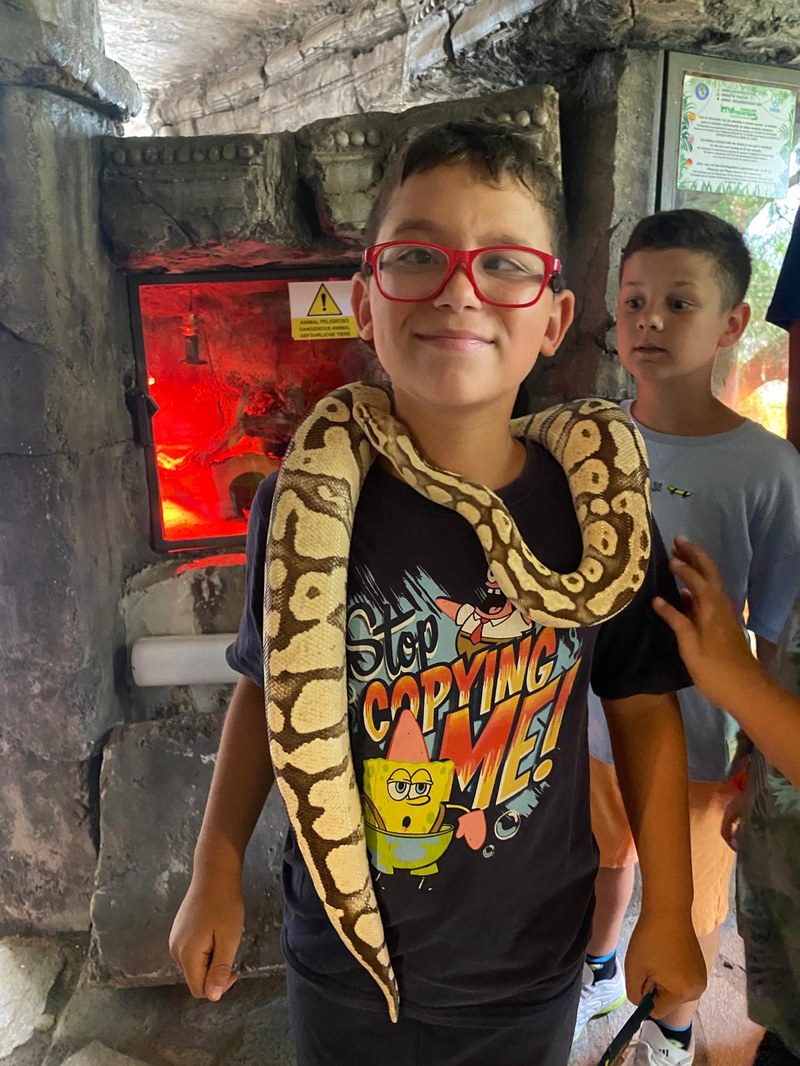 Participante posando con una serpiente de peluche al cuello, en la visita a Maroparque.