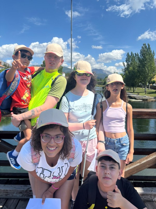 Grupo de participantes mirando a cámara con gorras, sobre un puente.