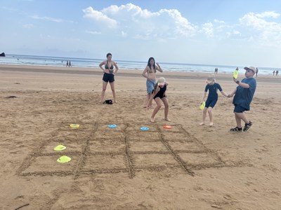 Participantes jugando al tres en raya en la arena de la playa